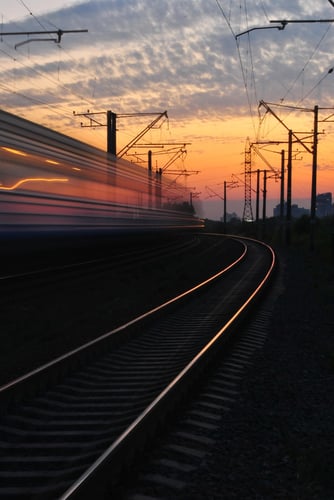A train travelling at high pssed under a sunset sky.